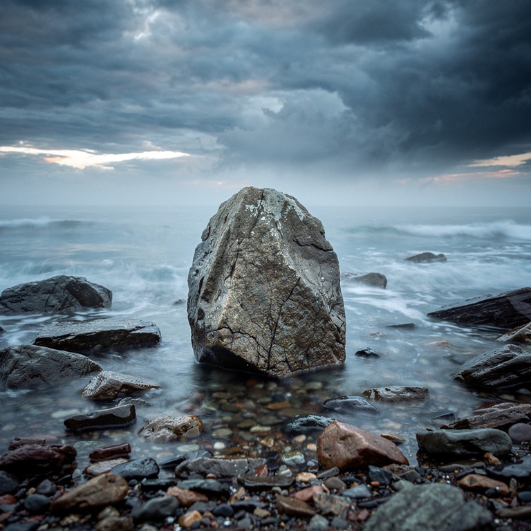 A rugged, weathered stone on a rocky shoreline, with waves g... | ShopAyahuascaRetreats