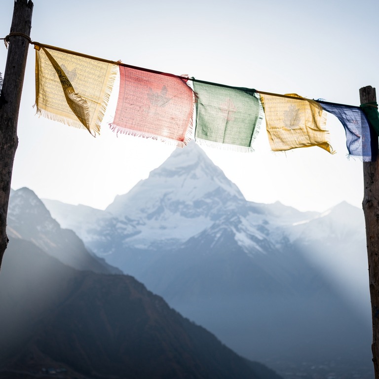 Prayer flags fluttering against a Himalayan peak | ShopAyahuascaRetreats